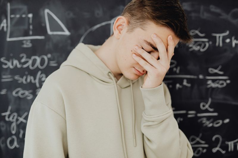 Student feeling overwhelmed near a blackboard